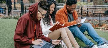 giovani seduti su di un prato con libri e pc